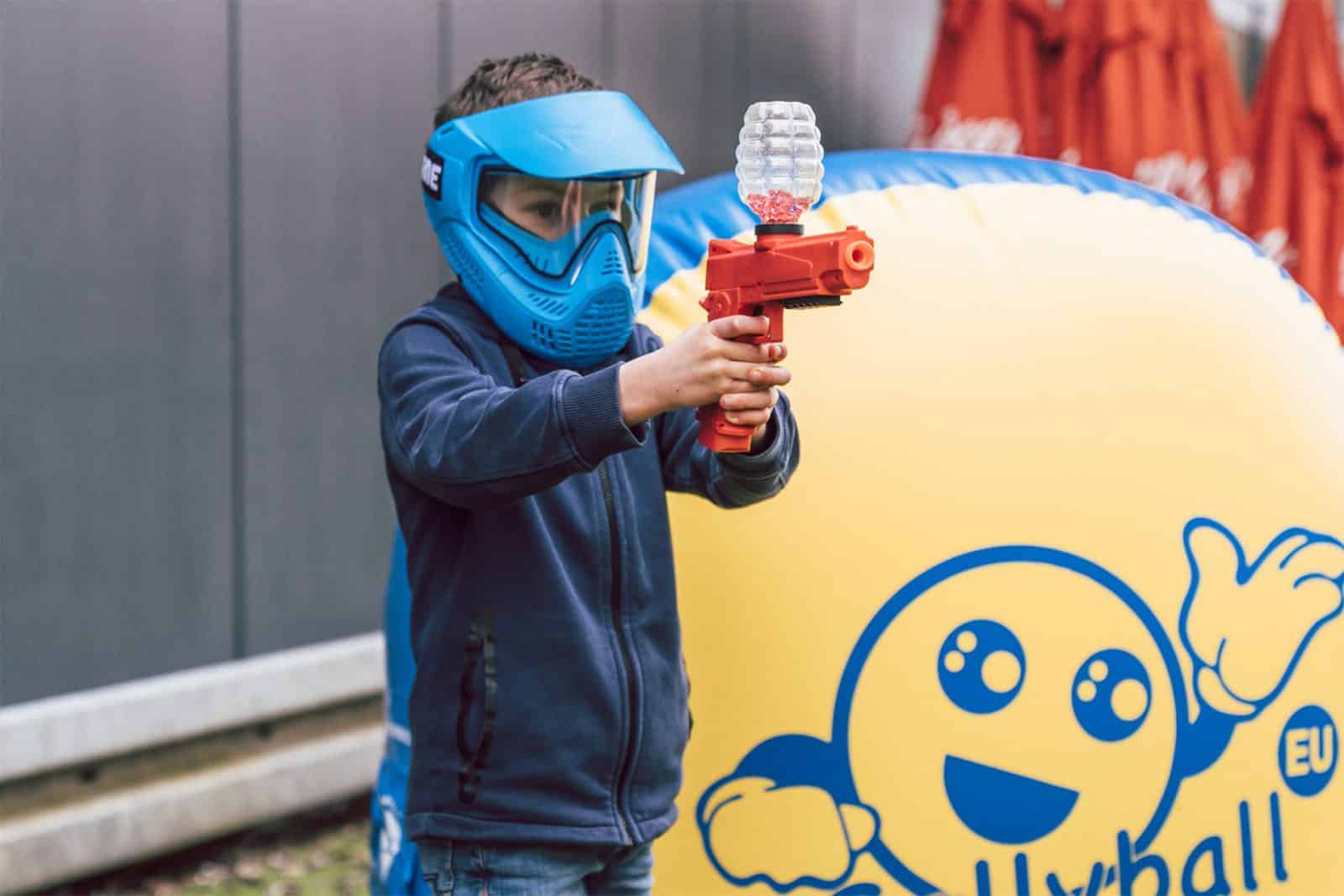 Jongen met helm en gellyblaster achter een obstakel