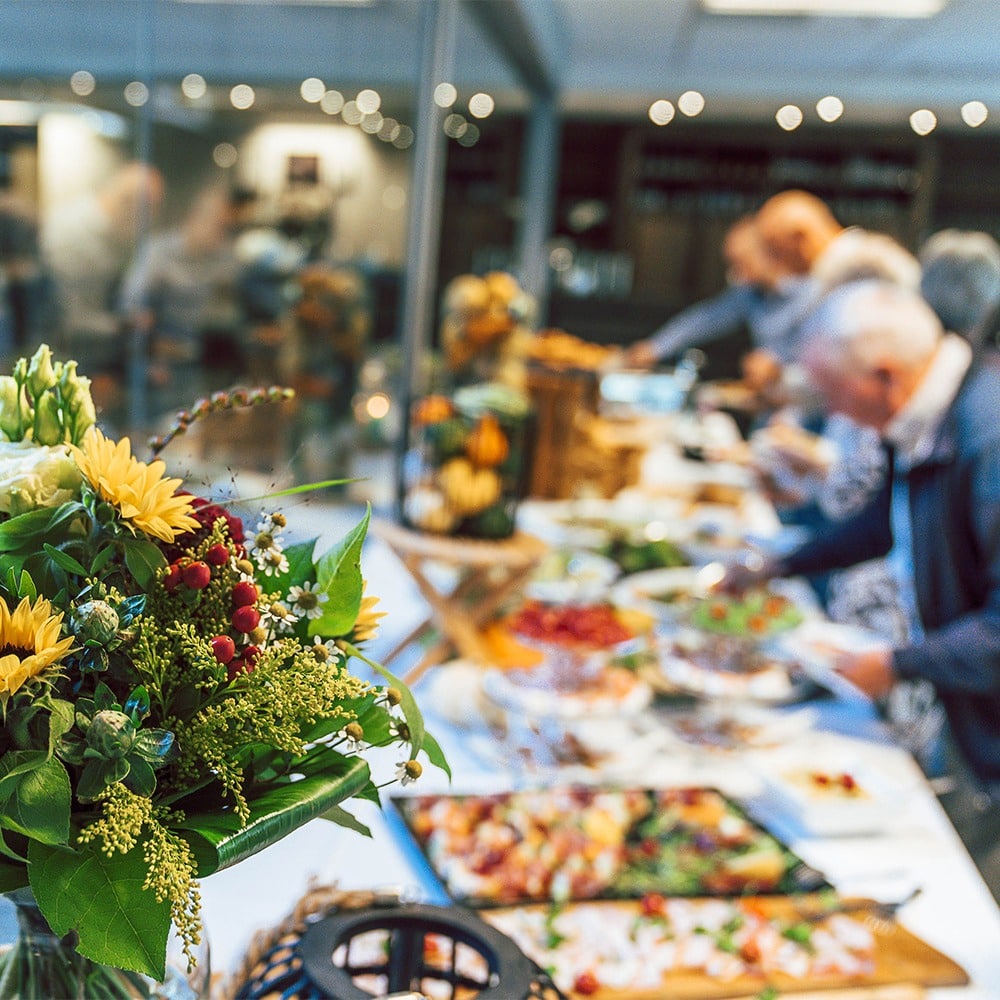 Gasten aan het ontbijtbuffet met een bloemstuk op de voorgrond