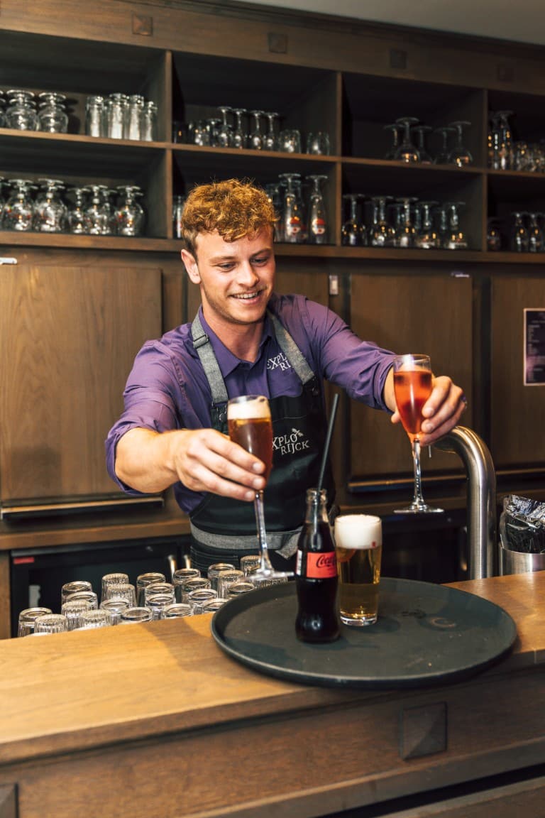 Een barman schenkt een glas in aan de toog